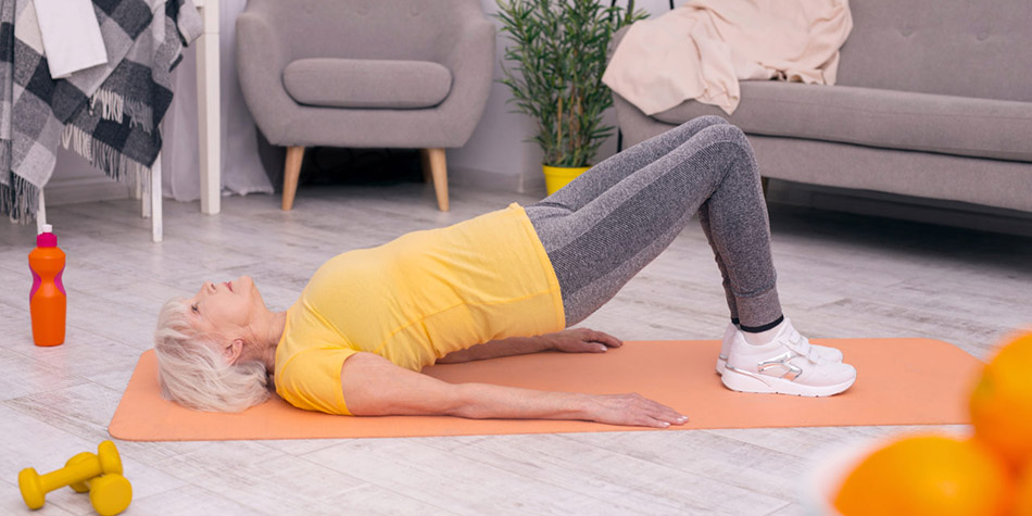 An older woman does a pelvic tilt exercise to strengthen her back.