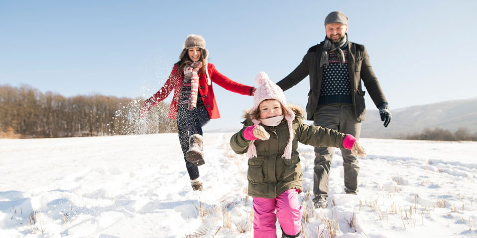 A family walks outside in the snow.