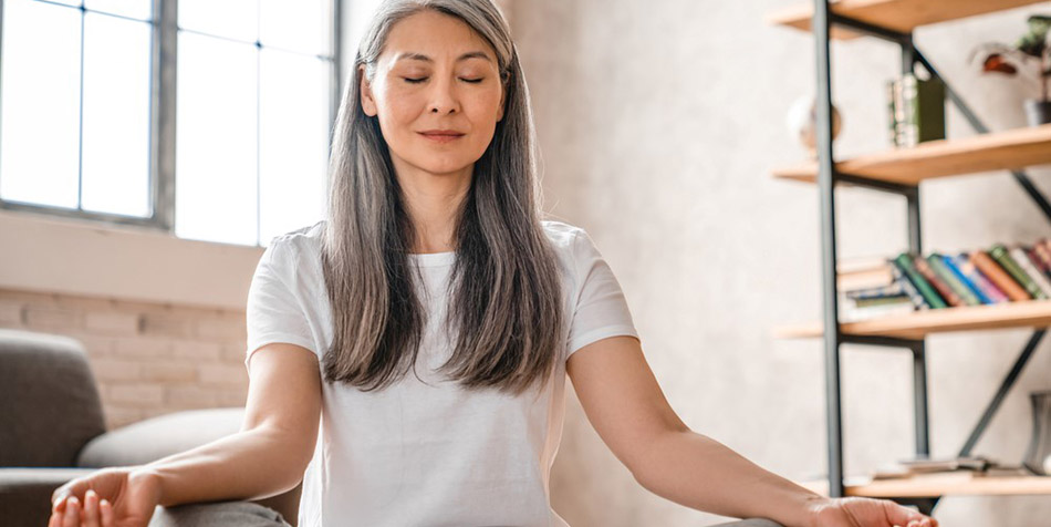 A woman meditating in her living room.