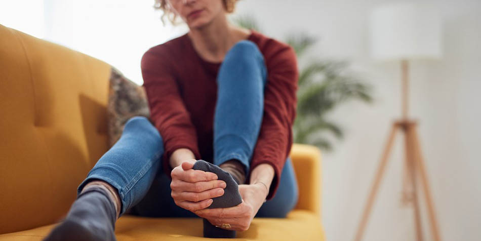 A woman holds her foot in her hands.